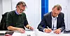 Terje Mikkelsen, forundssekretær i Norsk Arbeidsmandsforbund signerer avtalen som sendes nedover av Vidar Berg, konsernsjef i Nokas.