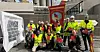 Renholdere og industriarbeidere samlet seg med fane utenfor Heidelberg Materials under renholdsstreiken 15. mai. Oppe fra venstre: Barbara Thompson, Gro Kimerud, Risyanti Aabelvik, Horia Ahmad, Grethe Gøytil, Jørn Bakken, Tom Jakobsen og Espen Eriksen. Nede fra venstre: Amleset Fekle, Mohamed Doohajoog, Ahmad Ahmad, Elyn Nilsen og Karl Erik Nicolaisen.