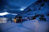 PRISGITT NATUREN: Bygninger, siloer og verksted ligger utsatt til ved foten av fjellet som om vinteren er dekket av livsfarlige snømasse. Her mørkner det av dag, og morgenskiftets kvinner og menn skal ta båten hjem fra jobb.