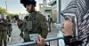 Palestinsk kvinne venter på at israelske soldater skal slippe henne gjennom et militært sjekkpunkt på Vestbredden.
