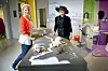 Ingeborg Apall-Olsen og Gro Røde, for anledningen iført hatten til ei fabrikkjente, ved modellen av  Akerselva, der vannet ble farget alt ettersom hvilken farge tekstilfabrikkene dumpet i elva. Selv rottene ble farget.