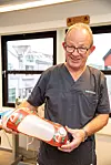 LÆREMESTEREN: Ortopeditekniker Bjørn Grafsrønningen var Maren Grimstad Bangs læremester. Han viser en protese hvor brukeren fikk dekorert den med farge og logo til favorittforballaget. Hylsen kalles for mykhylse eller rammeprotese der den har ’’vinduer’’, ifølge Bang. Innerhylsen er da altså myk og rammen rundt er forsterket med karbon. På de områdene med vindu på mykhylsen er det mer fleksibelt, beregnet for å kunne gi litt mer etter, men at den samtidig har god støtte med den forsterkede rammen rundt.