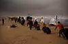 Migrantarbeidere rømte unna urolighetene i Libya. Her bærer de eiendelene sine under en sandstorm i en flyktningleir i Ras Ajdir på grensen mellom Tunisia og Libya i mars 2011.
