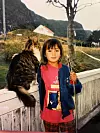 OPPVEKST: Monica Goksøyr (7) på barndomsøya Runde i havgapet, sammen med katten hennes Lassie og en improvisert fiskestang. Hun er stadig tilbake, og har arvet bestemoras gamle hus med en søster.