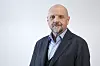 Tor Asmund Godal i mørk jakke foran en lys, nøytral bakgrunn.