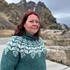 Charlotte Heimtoft Lassesen i grønn mønstret genser foran steinete fjell og overskyet himmel.