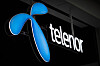 Blå Telenor-logo og hvit tekst på en mørk fasade.