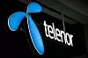 Blå Telenor-logo og hvit tekst på en mørk fasade.
