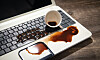 Kaffekopp og sølt kaffe på tastatur og håndleddsstøtte på en bærbar PC.