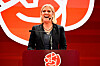 Magdalena Andersson taler ved en rød talerstol foran Socialdemokraternas symbol.