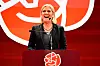Magdalena Andersson taler ved en rød talerstol foran Socialdemokraternas symbol.