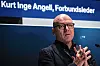 Kurt Inge Angell med briller står foran en mørkblå bakgrunn og holder hendene samlet.