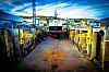 Utsikt gjennom en industriell tørrdokk i Harstad med gule rekkverk, arbeidsutstyr og kraner.