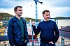 To menn foran verftet Hamek i Harstad, med en høy blå kran og havnen i bakgrunnen.