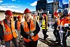 Statsråd i hjelm og oransje verneklær står sammen med andre t på en byggeplass i Oslo.