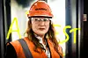 Direktør i Arbeidstilsynet med Skanska-hjelm, vernebriller og oransje vest i et mørkt bygg.