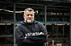 Oleg Grygoriuk står med korslagte armer foran en industriell havnekonstruksjon.