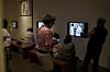 Besøkende ser på kunst og en skjerm i en dunkelt belyst sal på Munchmuseet.