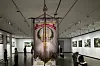 Museumssal med en stor hengende fagforeningsfane i sentrum og kunstverk langs veggene.
