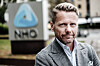 Kjetil Staalesen i grå blazer foran et skilt med NHO-logoen.