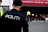 Politibetjent i forgrunnen mens demonstranter sitter samlet under en Fosen-protest.