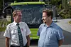 Øyvind Selnes og Per Ole Melgård står foran en grønn buss ved en skogkledd vei.