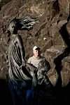 Jan Harsem står foran en skulptur av en kvinne og et barn i et steinete landskap.