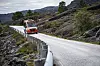 Rød Skyss-buss på en smal, svingete vei gjennom et steinete fjellandskap i Solund.