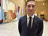 Andreas Bjelland Eriksen i mørk dress foran kunstverk og en rikt dekorert sal.