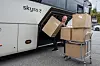 Skyss-buss med sjåfør som flytter pappesker til en tralle.