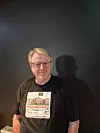Rune Ask står foran en mørk vegg iført en svart T-skjorte med politisk budskap om pensjon.
