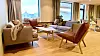 Lys stue med sofaer, lenestoler, bord og planter ved Bodø ungdomssenter.