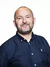 Portrett av bussjåfør Stig Arild Hærø i mørk skjorte mot hvit bakgrunn.