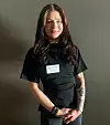 Portrett av Kaisa Maria Almenning Korvanen-Mæland i svart skjorte foran en mørk vegg.