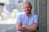 Staale Andre Bergersen står med armene i kors foran en mørk fasade.