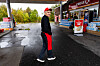 Normohammad Rezaei står på en våt Circle K-stasjon iført svart jakke, rød bukse og rød caps.