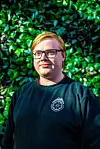 Johannes Fåberg Moldung iført mørk genser foran frodig grønt løvverk i Bergen.