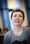 Portrett av Ingerid Marie Utvik i et lyst interiør, iført grå topp og med øredobber.