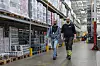 Tomasz Kapica og Sindre Mortensen går mellom høye pallereoler på Coops lager i Tromsø.