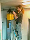 Eystein Garberg står på en stige innendørs og skjøter fiber.