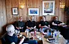 Eystein Garberg og flere personer sitter samlet rundt et dekket bord i et rom med villmarkspanel.