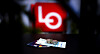Belyst LO-logo i bakgrunnen med dokumenter og penger på et mørkt underlag.