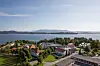 Flyfoto av campus Stord med bygninger, veier, fjord og fjell i bakgrunnen.