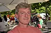 Atle Høie fotografert på en utendørskafé under parasoller, med grøntområder og mennesker i bakgrunnen.