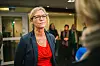 Nina Melsom i mørk jakke og rød bluse, med flere personer i bakgrunnen.