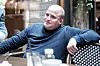 Stian Tveitan sitter ved et bord på en kafé iført mørk blå genser.